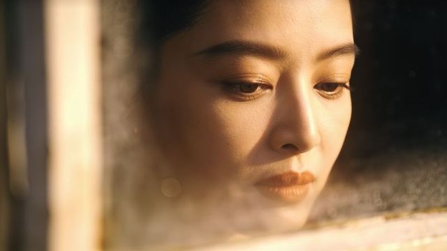 Gazing asian woman leaning against fogged window, contemplative warm golden-hour portrait