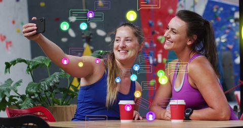 Two women taking selfie with interactive media icons