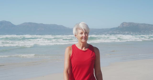 Portrait of happy senior caucasian woman wearing sports clothes smiling at beach. Retirement, healthy and active lifestyle.