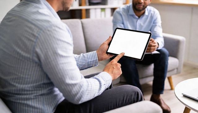 Colleagues Collaborating on Tablet in Modern Office Lounge Showing Blank Screen for Mockup