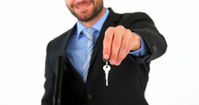 Businessman extending house key towards camera, suggesting completion of real estate transaction or new home ownership. Useful for illustrating real estate services, property investment articles, or advertisements for real estate agents.