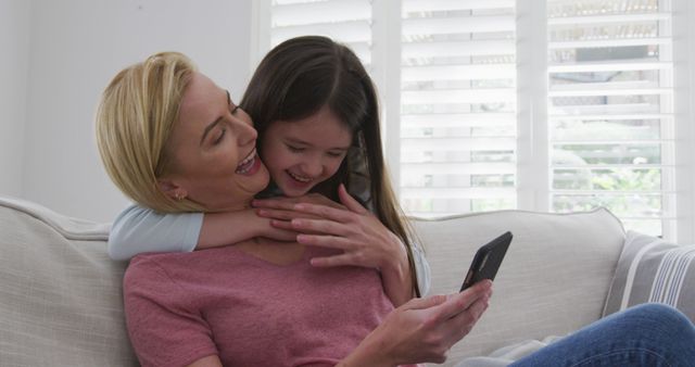 Happy Mother and Daughter Bonding while Looking at Smartphone on Couch - Download Free Stock Images Pikwizard.com