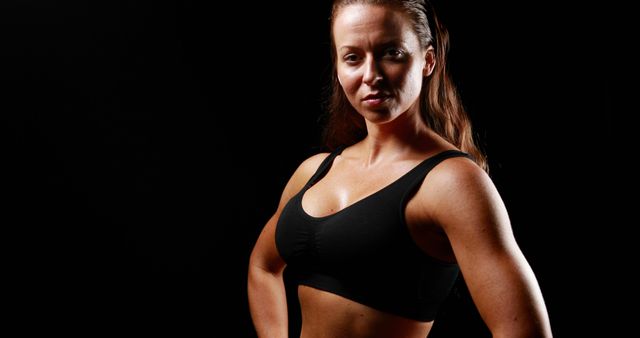 Confident Female Athlete in Sports Bra Posing Against Dark Background - Download Free Stock Images Pikwizard.com