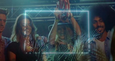 Friends celebrating on stage while woman lifting trophy under neon frame and tropical glow