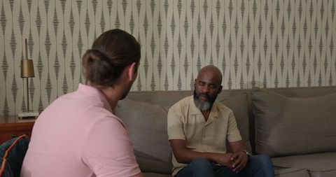 Two men engaging in serious conversation on living room sofa