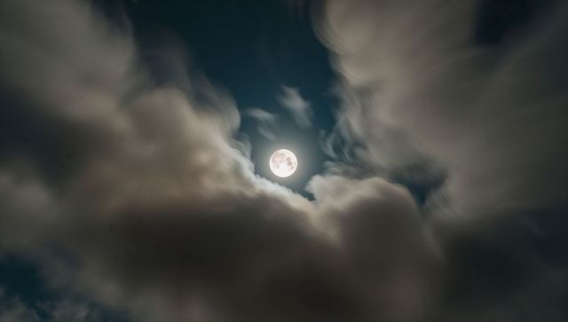 Luminous Full Moon Illuminating Dramatic Night Sky with Mystic Clouds