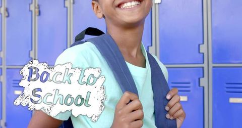 Smiling student holding navy backpack at blue lockers in mint t-shirt with back to school graphic