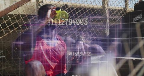 Athlete drinking from shaker bottle resting by chain-link fence with augmented hud overlay