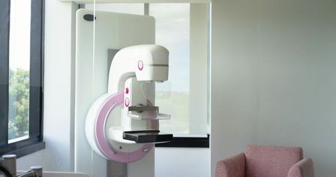 Mammography unit standing in modern radiology clinic with pink chair and window light