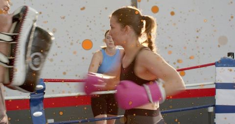 Female Boxer Training Hard with Pink Gloves Hitting Focus Mitts in Boxing Ring