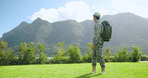 Soldier in camouflage gear overlooking majestic mountains