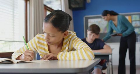 Focused student writing in classroom, engaged learning environment