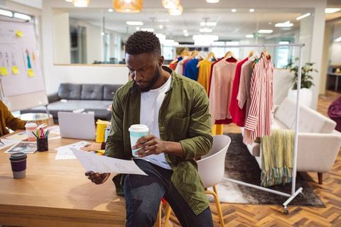 Fashion designer analyzing sketches in modern stylish office