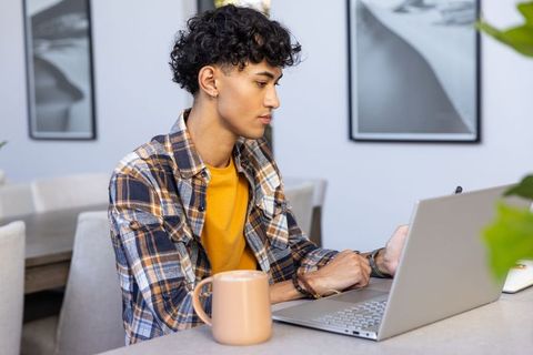 Young man working on laptop with stylus at home desk