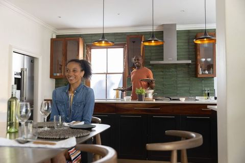 Couple preparing cozy dinner in modern kitchen with island and pendant lights