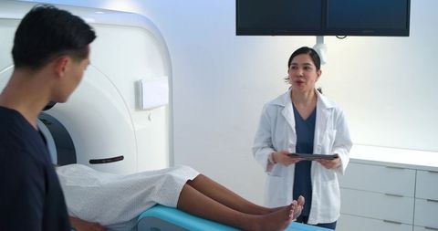 Radiologist preparing patient for ct scan in modern imaging suite with tablet monitors