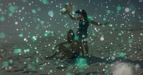 Young Couple Relaxing on Sandy Beach with Sunhat, Towel and Teal Bokeh Light Effects