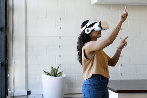 Woman using virtual reality headset in modern office, interacting with virtual interface
