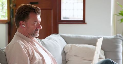 Mature Man Working from Home Sitting on Sofa with Laptop