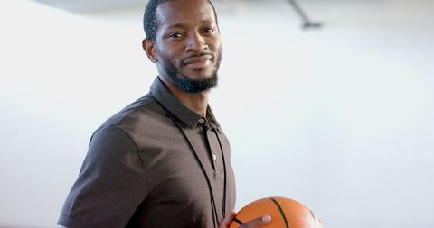 Confident Coach Holding Basketball on Outdoor Court