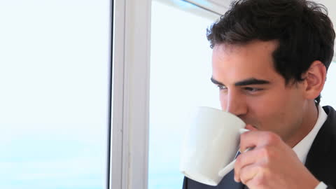 Business Professional Drinking Coffee by Window