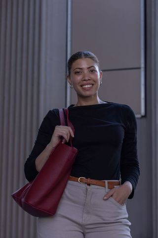 Confident african american professional woman standing in lobby holding red tote bag