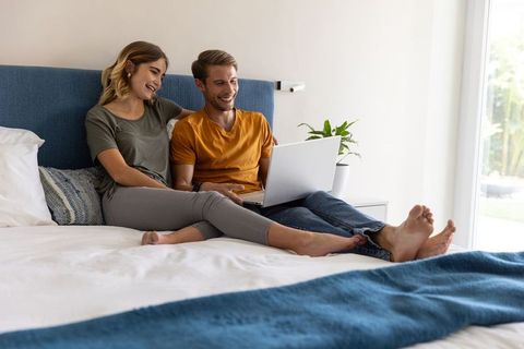 Couple Enjoying Bedroom Relaxation Sharing Laptop