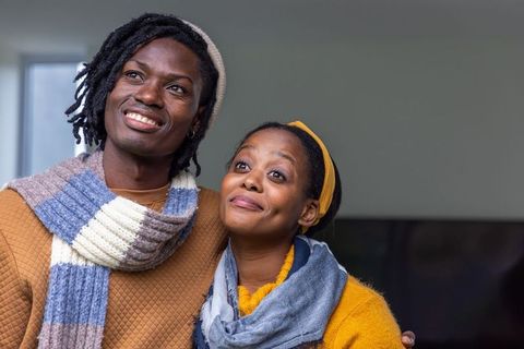 Young african american couple smiling, looking upward, wearing knit scarves and cozy layers