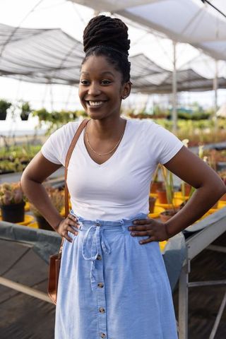 African american woman smiling in greenhouse among succulents and yellow pots