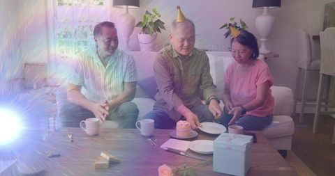 Multigenerational group celebrating birthday at home with cake, gifts and cozy living room