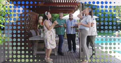 Multigenerational friends enjoying summer poolside party under wooden pergola