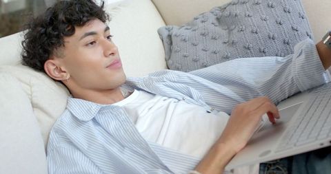 Young Man Relaxing and Typing on Laptop in Comfortable Living Room