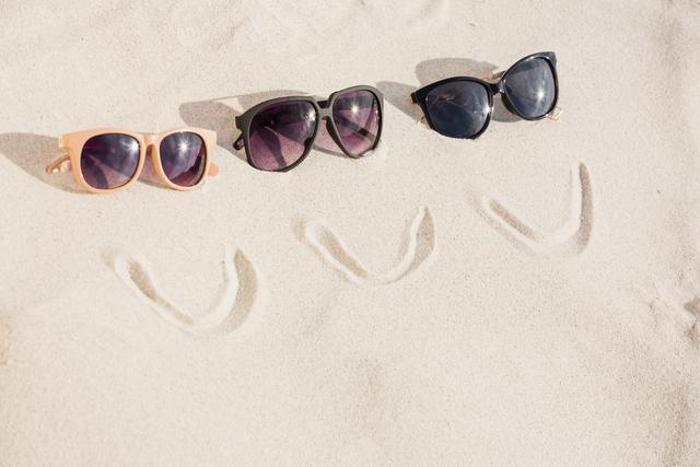 Smiley face and three sunglasses on sand at beach