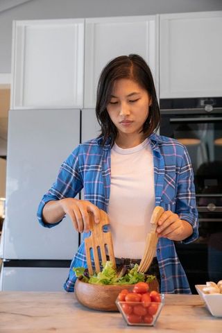 Asian Woman Preparing Fresh Salad in Modern Kitchen