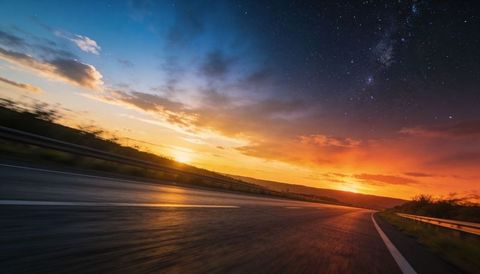 Curving highway at dusk with reflective asphalt, vibrant sunset glow and milky way sky