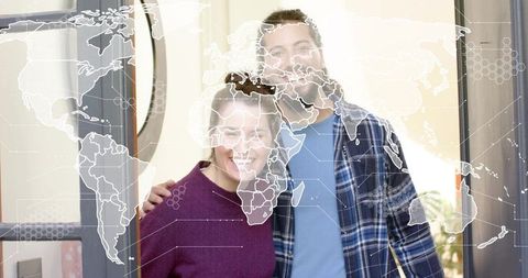 Smiling couple embracing at front door with digital world map overlay welcoming homeowners