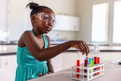 African american girl conducting colorful test tube experiment in school lab