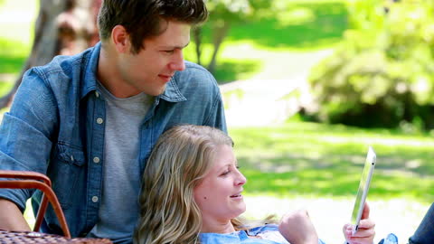 Couple Relaxing Outdoors with Tablet in Park Setting