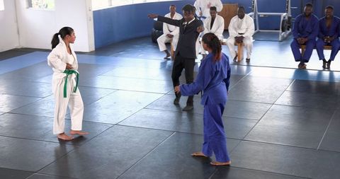 Female Karate Competitors Sparring with African American Referee Judging