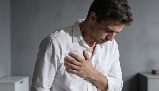 Man experiencing chest pain holding heart overlay medical emergency concept