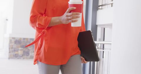 Businesswoman Carrying Coffee and Laptop at Office