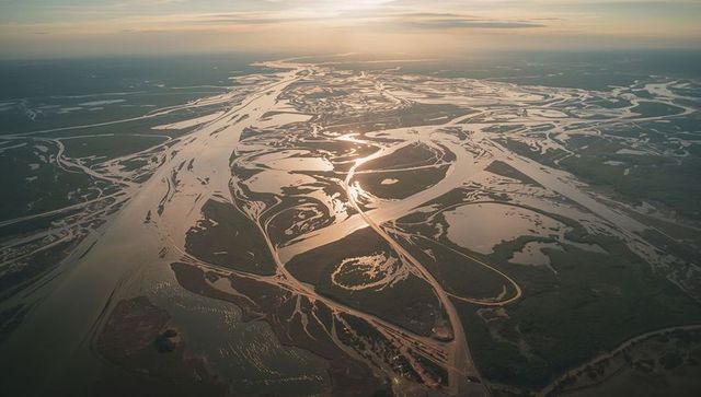Aerial sunset braided river channels flowing across river delta with sandbars and mudflats