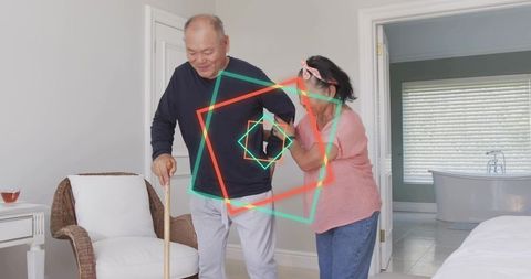 Elderly man receiving at-home mobility support from partner helping with wooden cane