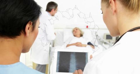 Medical team reviewing spinal x-ray on tablet at bedside in modern hospital ward