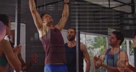 Motivated group cheering athlete performing pull-ups in modern gym