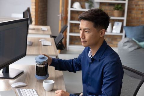 Professional using french press at modern workspace