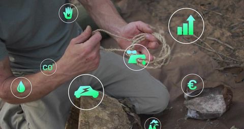 Outdoor craftsman kneeling tying natural rope in woodland with green sustainability icons