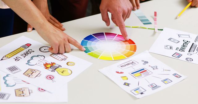 Graphic designers discussing over color swatch at desk in office