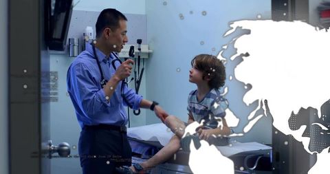 Asian doctor examining child with otoscope in pediatric clinic, stethoscope on neck
