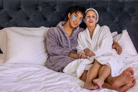 Diverse couple enjoying cozy at-home spa night with under-eye patches and plush robes